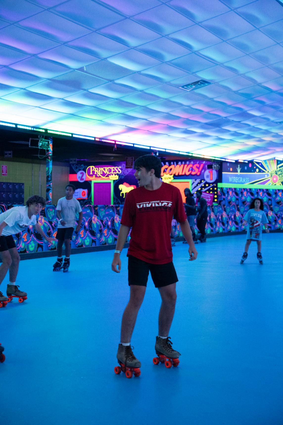Older kids enjoying a roller skating party in Valdosta with friends, music, and vibrant lights.